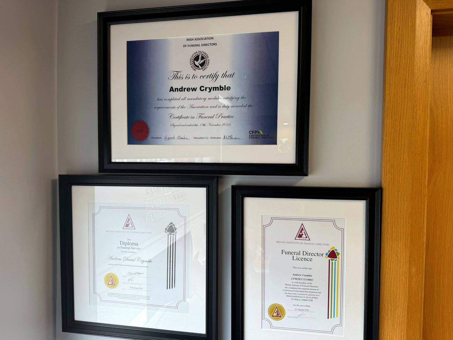 Andrew Crymble's framed funeral-director qualifications on the office wall.